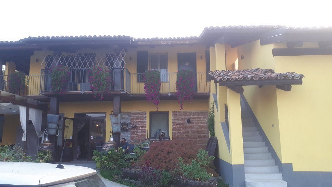 La cascina gialla con ballatoio fiorito e scala esterna